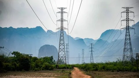 Big electrical pole next to a dirt path with mountains in the background, T.. Stock Photos