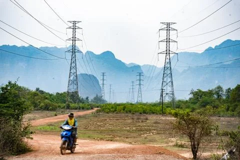 Big electrical pole next to a dirt path with mountains in the background, T.. Stock Photos
