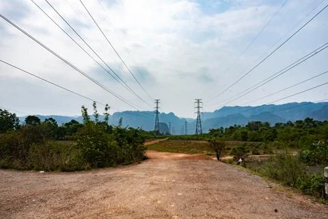 Big electrical pole next to a dirt path with mountains in the background, T.. Stock Photos