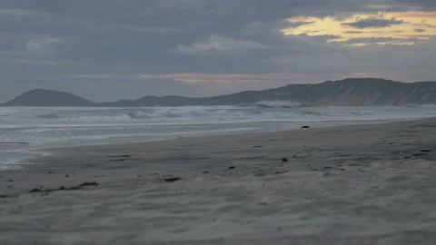 Big empty beach at sunrise, cliffs diving into the ocean, birds fly and sunrise 스톡 동영상 132167506