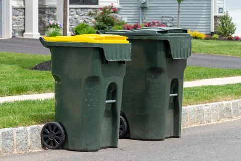Big empty green plastic trash garbage bin in front of the modern house Stock Photos