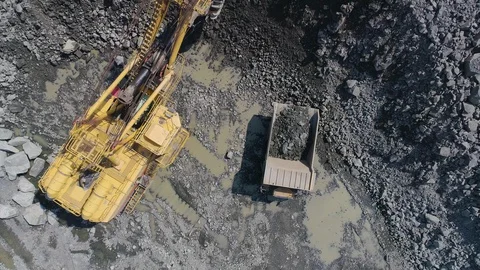 Big excavator loading granite into heavy dump truck drone top view Stock-Footage 129473285