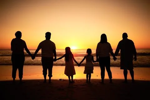 Big family silhouette on beach with sea waves, sunset on the horizon and holding Stock Photos