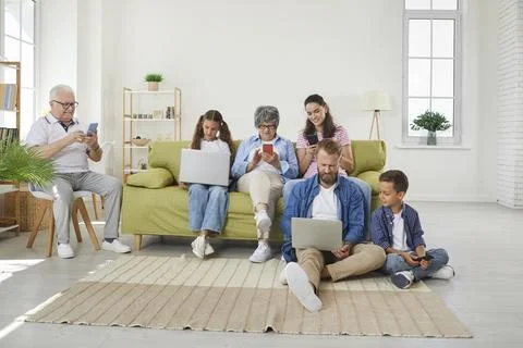 Big family using different electronic devices while sitting on sofa at home Stock Photos
