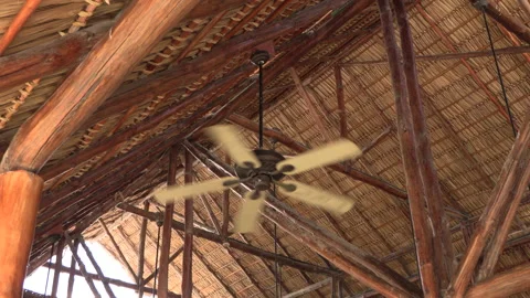 Big fan hanging from the ceiling spinning with a straw roof in the caribbean fan Stock Footage 170522443