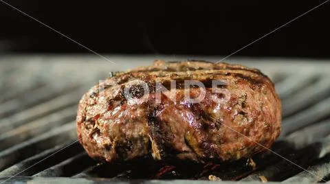 A big fat juicy burger cutlet comes to its readiness on the grill, heat and Stock Photos