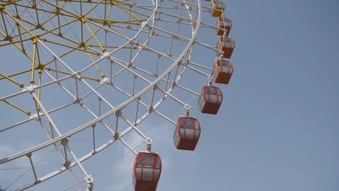 Big ferris wheel rotates at amusement park ride over clean blue sky close-up Stock Footage