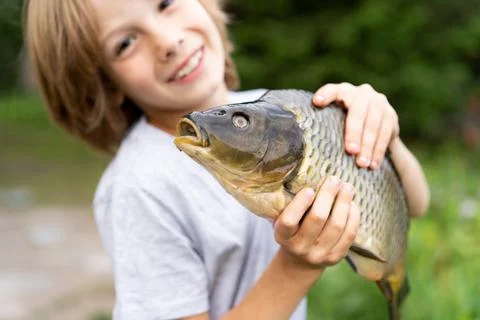 Big fish carp in the hands of a boy, fishing with a child, a young fisherman Foto stock
