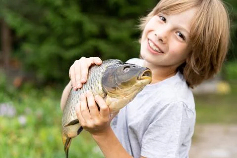 Big fish carp in the hands of a boy, fishing with a child, a young fisherman Stock Photos