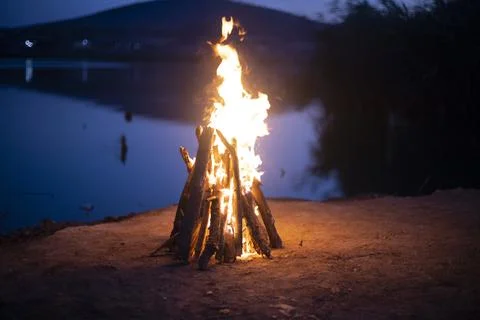 Big flame flutters in wind. Bonfire made of branches of fruit trees. Stock Photos