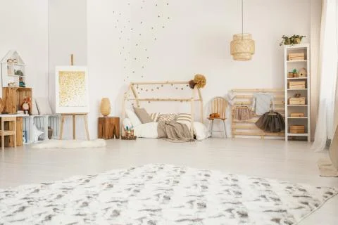 Big fluffy carpet placed on the floor in white Scandinavian style kid room in Stock Photos