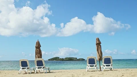 Big fluffy clouds fly above ocean and sand with beach chairs and closed Video stock 128064797