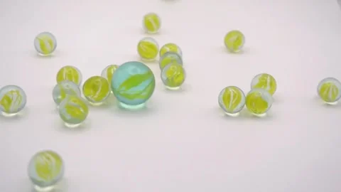 Big glass marble knocking small toy marbles on white background Vídeos de archivo 308866044