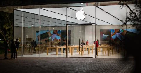 Big Glass Windows of Apple Store at night modern building Apple Logo Stock Photos