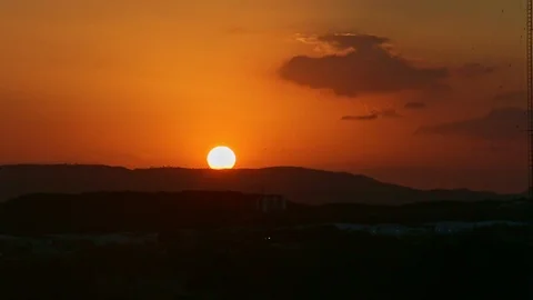 Big golden sun quickly sits down over black silhouette of low mountains Stock Footage 123668188