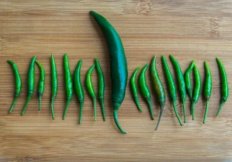 A big green chilli pepper in small Green chilli pepper on chopping block Stock Photos