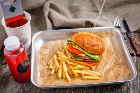 Big hamburger with three beef cutlet and vegetables with golden crispy french Stock Photos