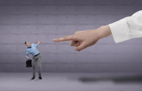 Big hand pointing at scared small businessman on grey background. Authority.. 스톡 사진