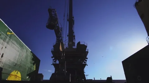 Big harbor crane unloading cargo from bulk carrier with blue sky in background Stock Footage 114509733