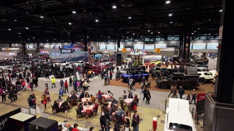 The big indoor auto show, filled with crowds of visitors walking throu Stock Footage 306436734