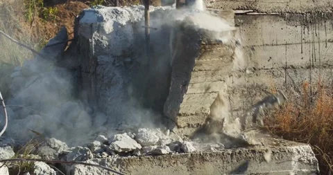 Big jackhammer machine is destroying a concrete wall, dust and rocks, 4k Stock Footage 155050377