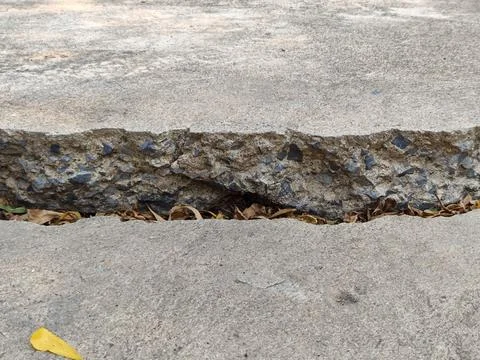 Big, long cracks and sinking spots have started to show up on the road. Stock Photos