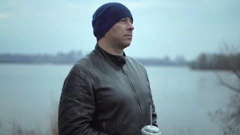 Big Man Looking Thoughtfully Ahead of Him With a Plastic Glass of Juice in Stock Footage 73904429