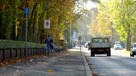 Big man riding a small bicycle on pavement in Autumn &amp; road traffic Stock Footage 44009853