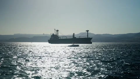 Big merchant ship with small boat passing by and parachute in see bay of akaba Stockbeeldmateriaal 308636733