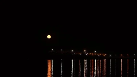 Big moon over the river, with night lights burning in the background Stock Footage 114631015