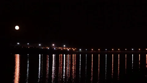 Big moon over the river, with night lights burning in the background Stock Footage 114631022