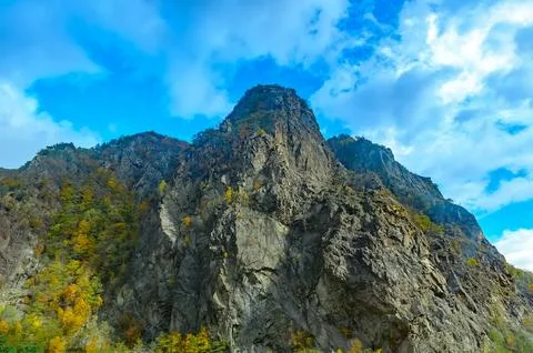 Big mountain and massive cliffs covered with trees in autumn colors blue sk.. Stock-Fotos