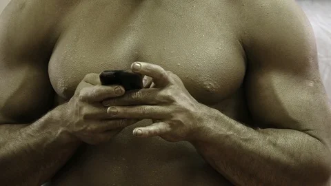 A big-muscle athlete writes a message on the phone Stock Footage 87988633