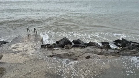 Big ocean waves flooding the concrete promenade in a coastal town Stock Footage 302584769