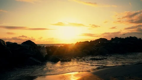 Big ocean waves hitting across huge stones with birds flying over sunset view. Stock Footage 106850195