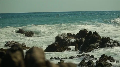 Big ocean waves rushing over jagged rocks in the sun Stock Footage 107003946