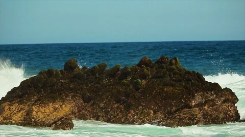 Big ocean waves rushing over jagged rocks by the beach. slomo D Stock Footage 107009194