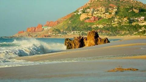 Big ocean waves rushing over jagged rocks by the beach with mountain. slomo Stock Footage 107009233