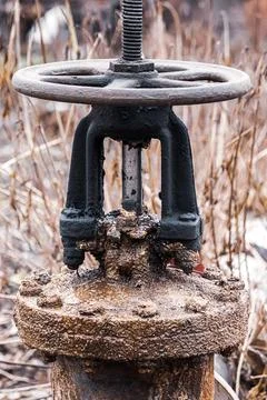 Big old rusty valve on pipe. Abandoned plumbing system. Stock Photos