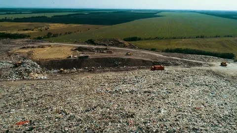 Big orange garbage truck moving among the wreckage. landfill. Stockbeeldmateriaal 114496853