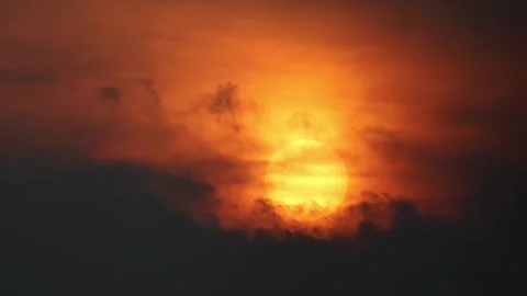 Big orange sun like a fire ball with dark clouds moving around it Stock Footage 283361681