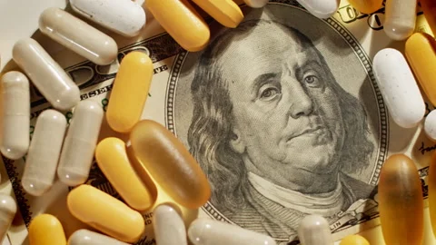 Big pharma conspiracy theory. Medical pills lying on top of US Dollar Bill Stock Footage