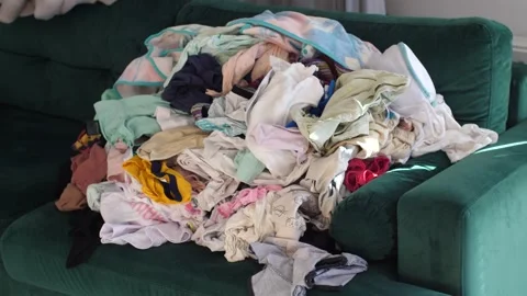 Big pile of clean clothes lying on a couch, laundry waiting to be folded Stock Footage 291669070