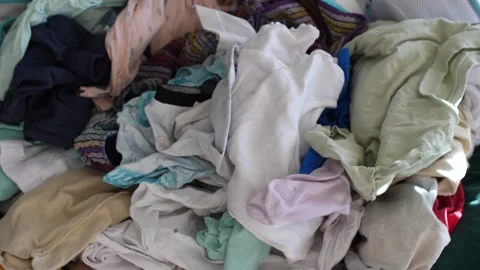 Big pile of clean clothes lying on a couch, laundry waiting to be folded Stock Footage 291669084