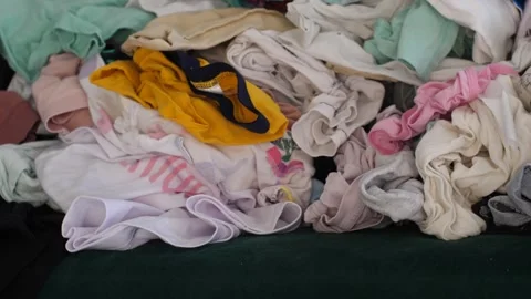 Big pile of clean clothes lying on a couch, laundry waiting to be folded Stock Footage 291669117