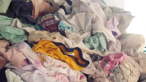 Big pile of clean clothes lying on a couch, laundry waiting to be folded Stock Footage 291669126
