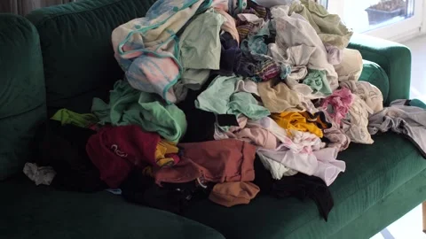 Big pile of clean clothes lying on a couch, laundry waiting to be folded Stock Footage 291669181