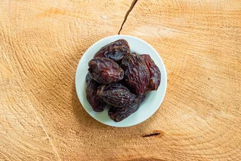 Big pitted dried dates on a small white plate set on a wooden boar top view 스톡 사진