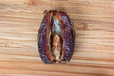 Big pitted dried opened date with visible seen inside set on a wooden boar to Photos