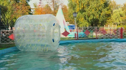 Big plastic bubble on water for children. Zorbing in swimming pool, activities. Stock Footage 169020964